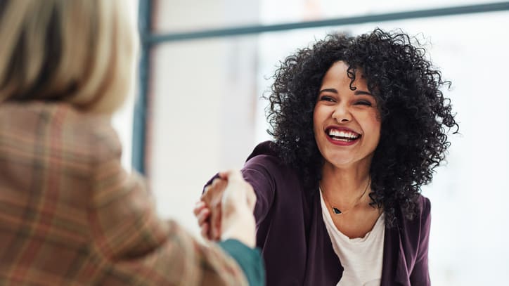 Two women shaking hands in an office.