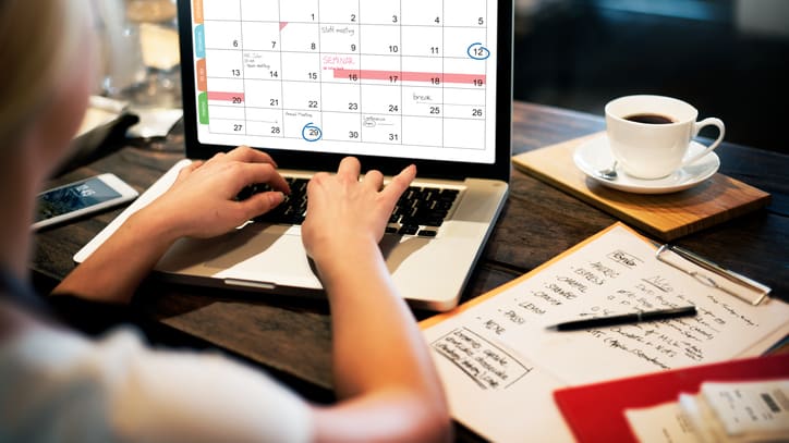 A woman using a laptop with a calendar on it.