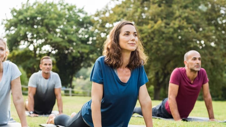 A group of people doing yoga in a park.