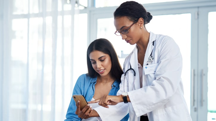 A doctor is showing her patience something on a phone