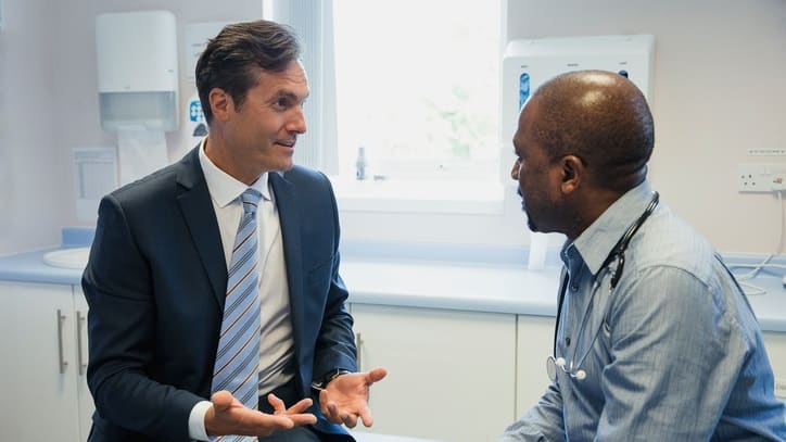 Two men talking in a doctor's office.