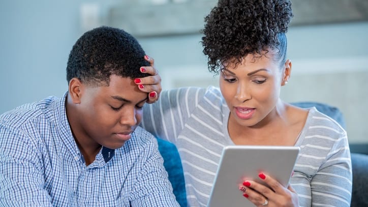 An woman and her son looking at a tablet computer.