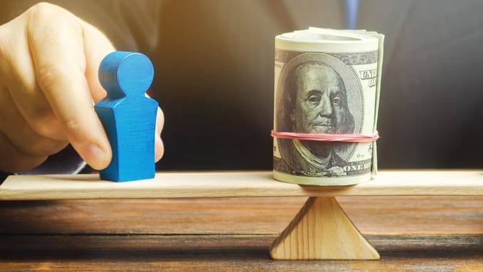 A businessman balances a dollar on a seesaw.