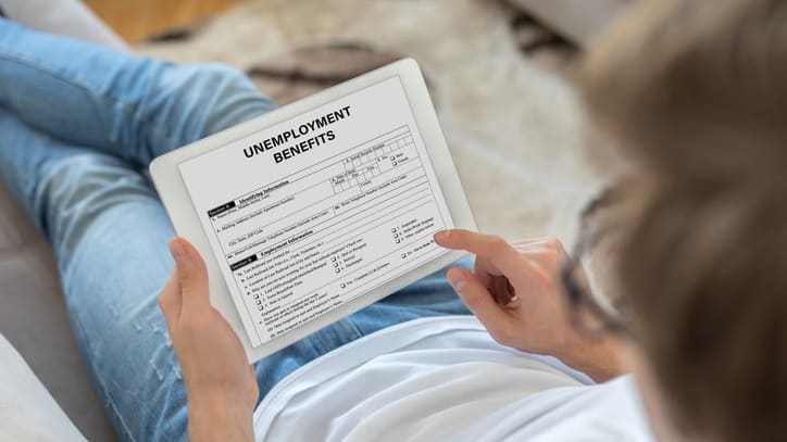 A man sitting on a couch holding a tablet with an employment application on it.