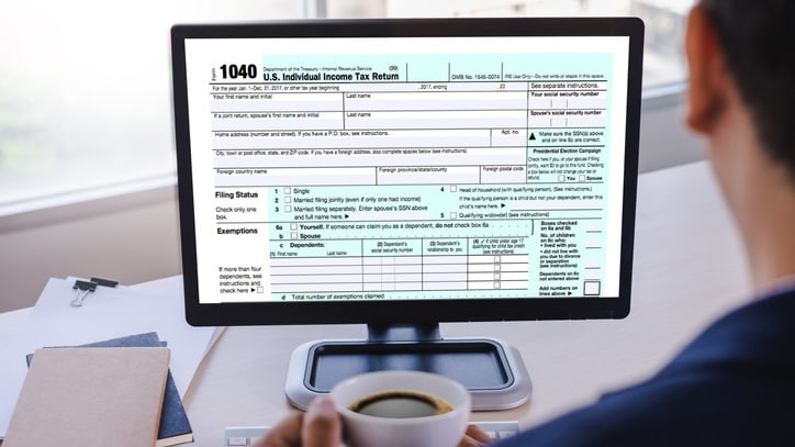 A man holding a cup of coffee while looking at the irs form.