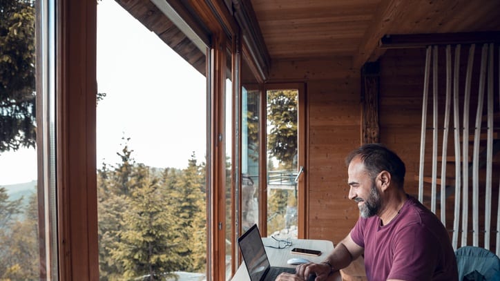 A man sitting in a cabin working on his laptop.