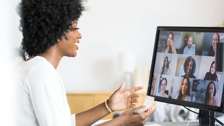 A woman in front of a computer screen showing a video conference.