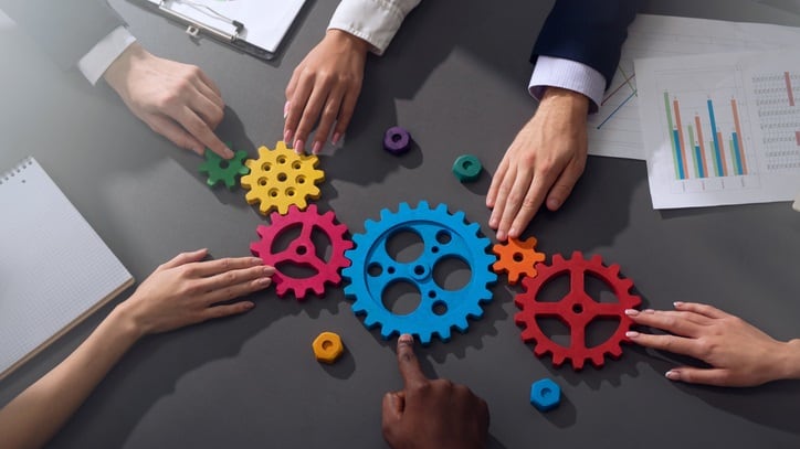 A group of people working together on a table with colorful gears.