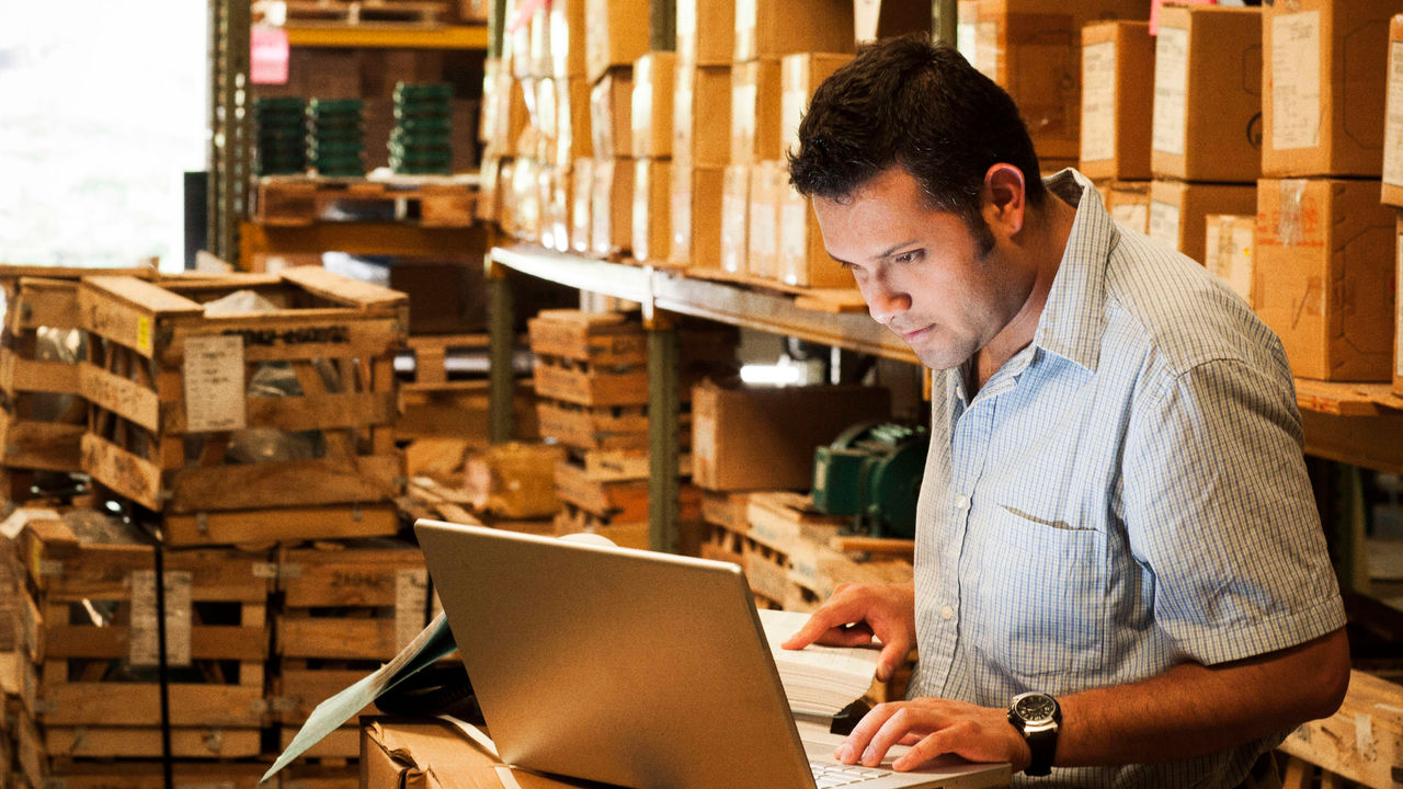 A man working on a laptop in a warehouse.