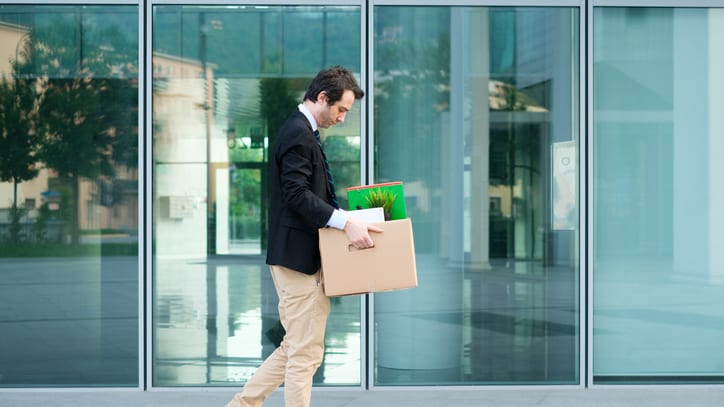 A businessman carrying a box in front of an office building.