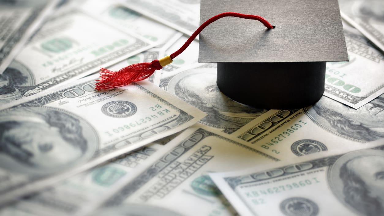 A graduation cap on top of a pile of money.