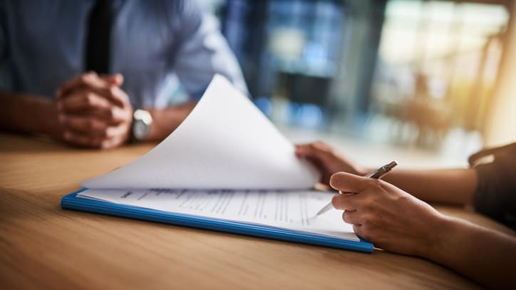 Two people signing a document at a table.