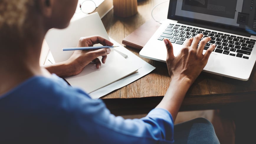 A woman working on a laptop at a desk.