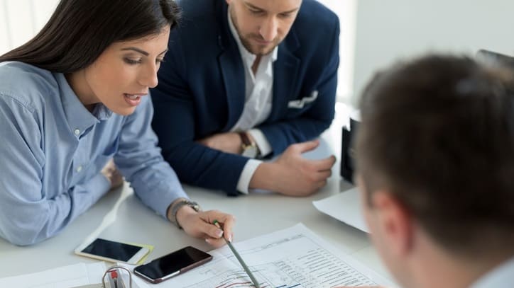 A group of people sitting around a table looking at papers.