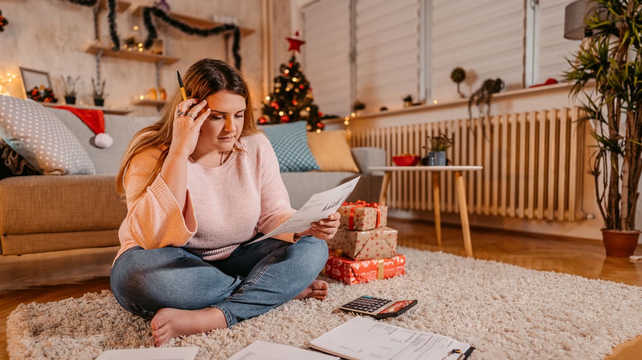 A woman sitting on the floor in front of a christmas tree.