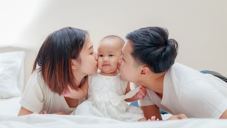 A young couple kissing their baby