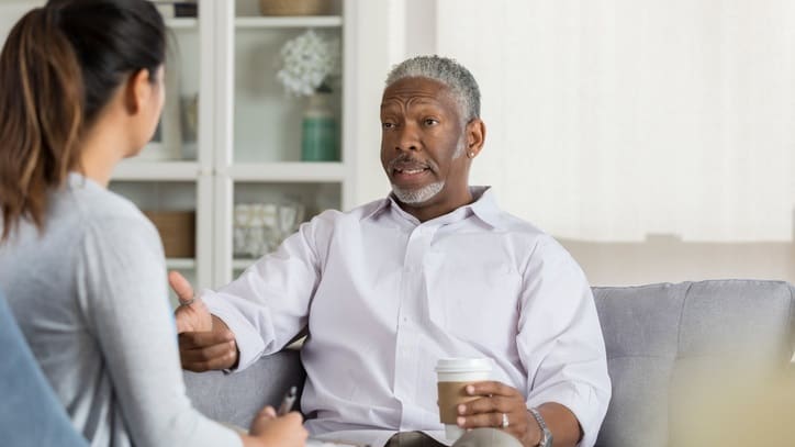 A man talking to a woman on a couch.