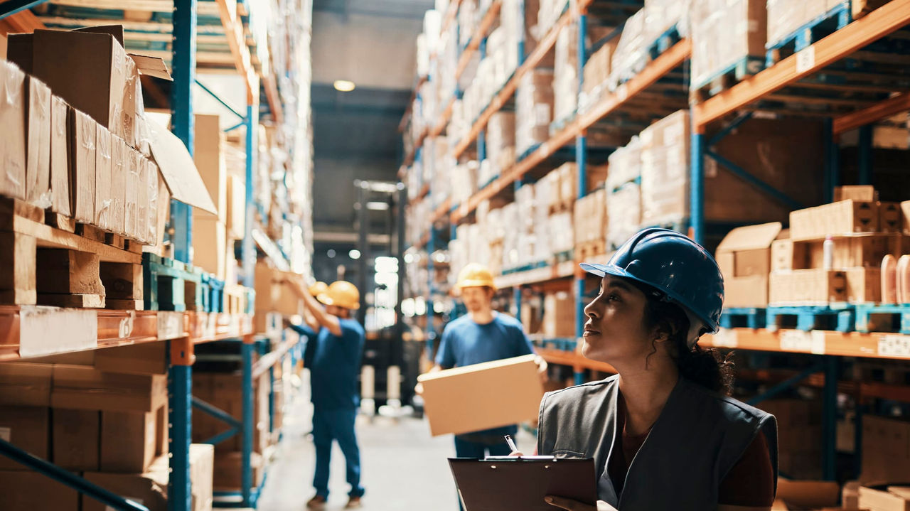 A worker in a warehouse holding a clipboard.