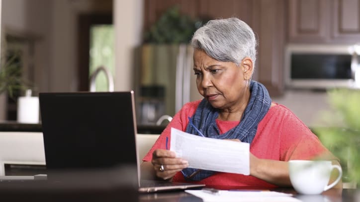 An older woman is using a laptop at home.