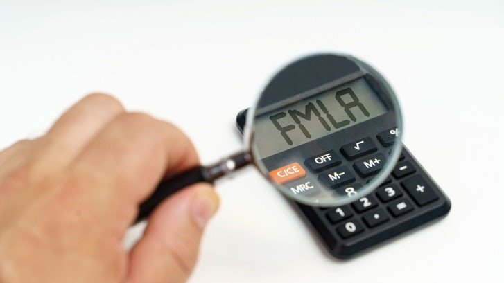 A person holding a magnifying glass over a calculator.