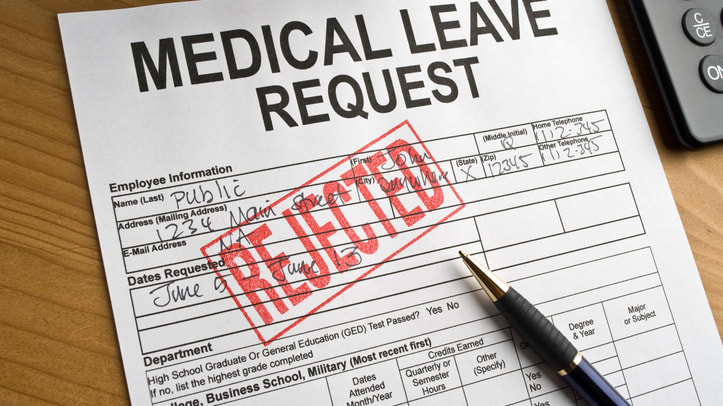 A medical leave request form on a desk with a pen and calculator.