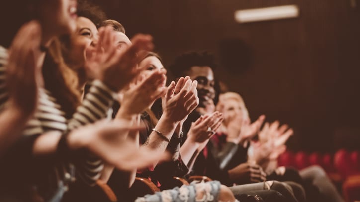 A group of people clapping in an auditorium.