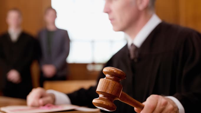 A judge is holding a gavel in a courtroom.