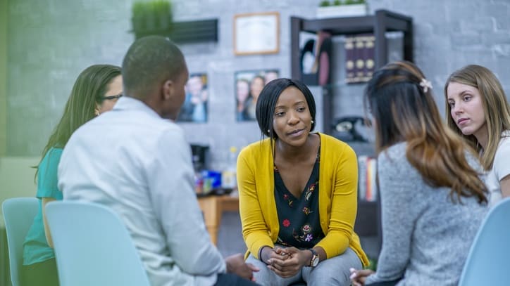 A group of people sitting around a table in an office.