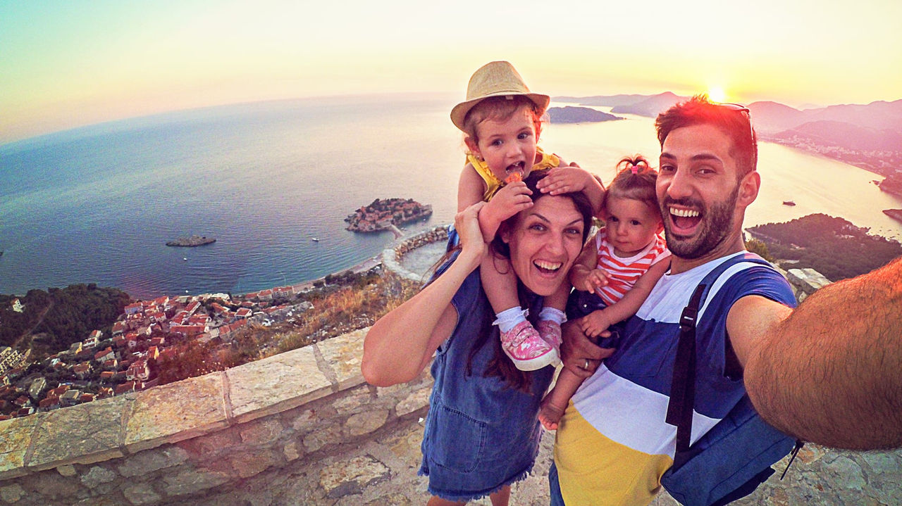 A family is taking a selfie on top of a mountain.