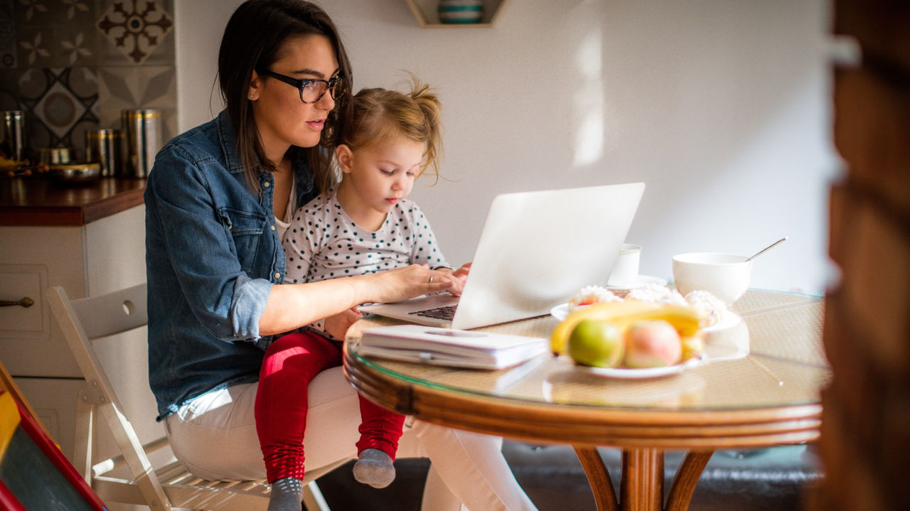 A woman and her daughter using a laptop at home.