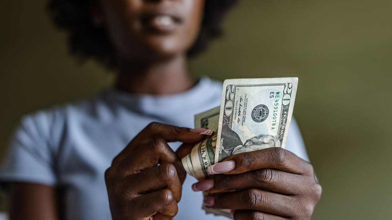 A woman is holding a stack of money in her hand.