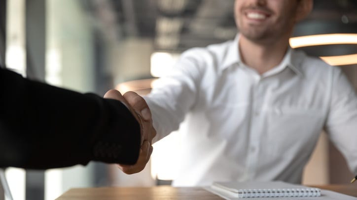 Two businessmen shaking hands at a desk.