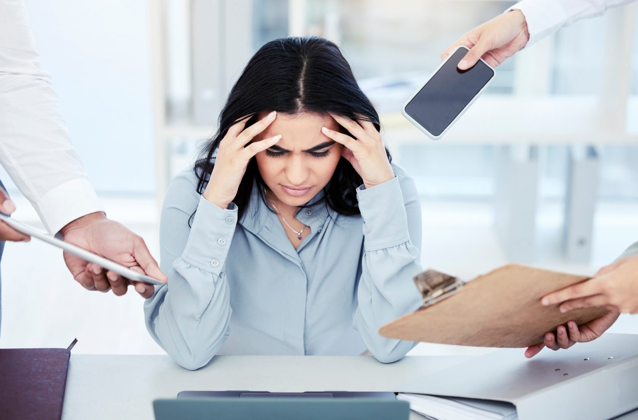 young woman stressed out with multiple tasks in an office 