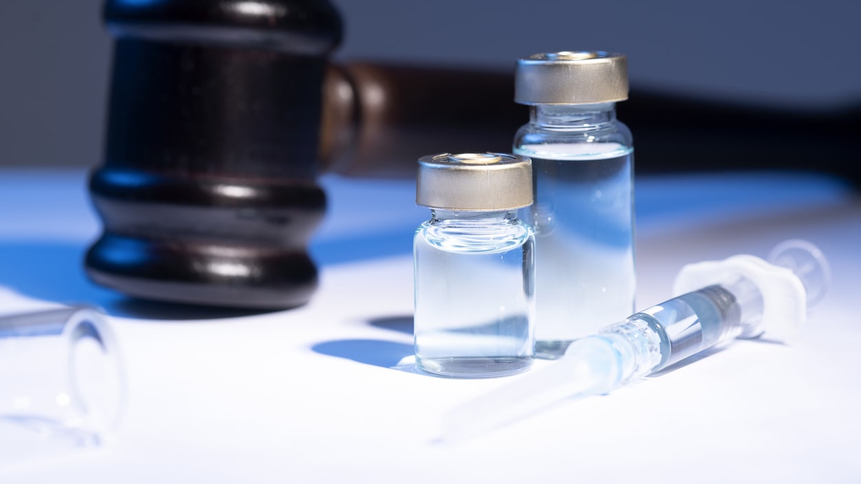 Two syringes and a gavel on a table.