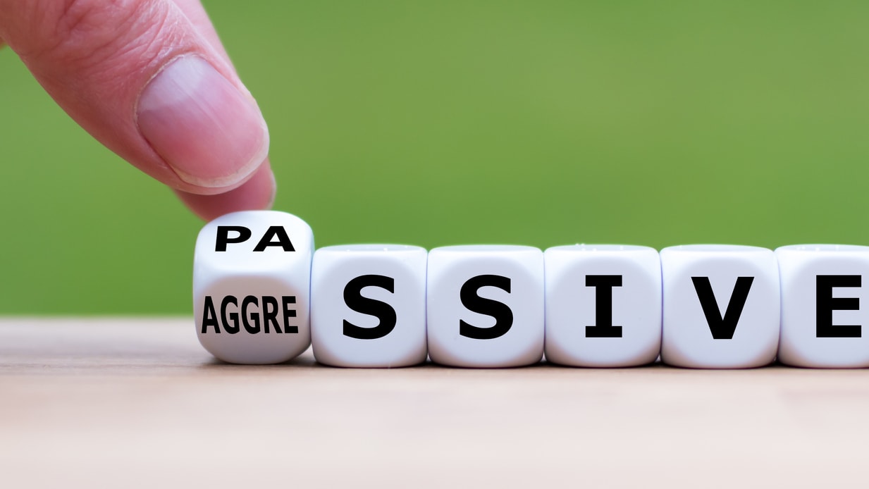 A hand is pointing to the word pasive on a wooden board.