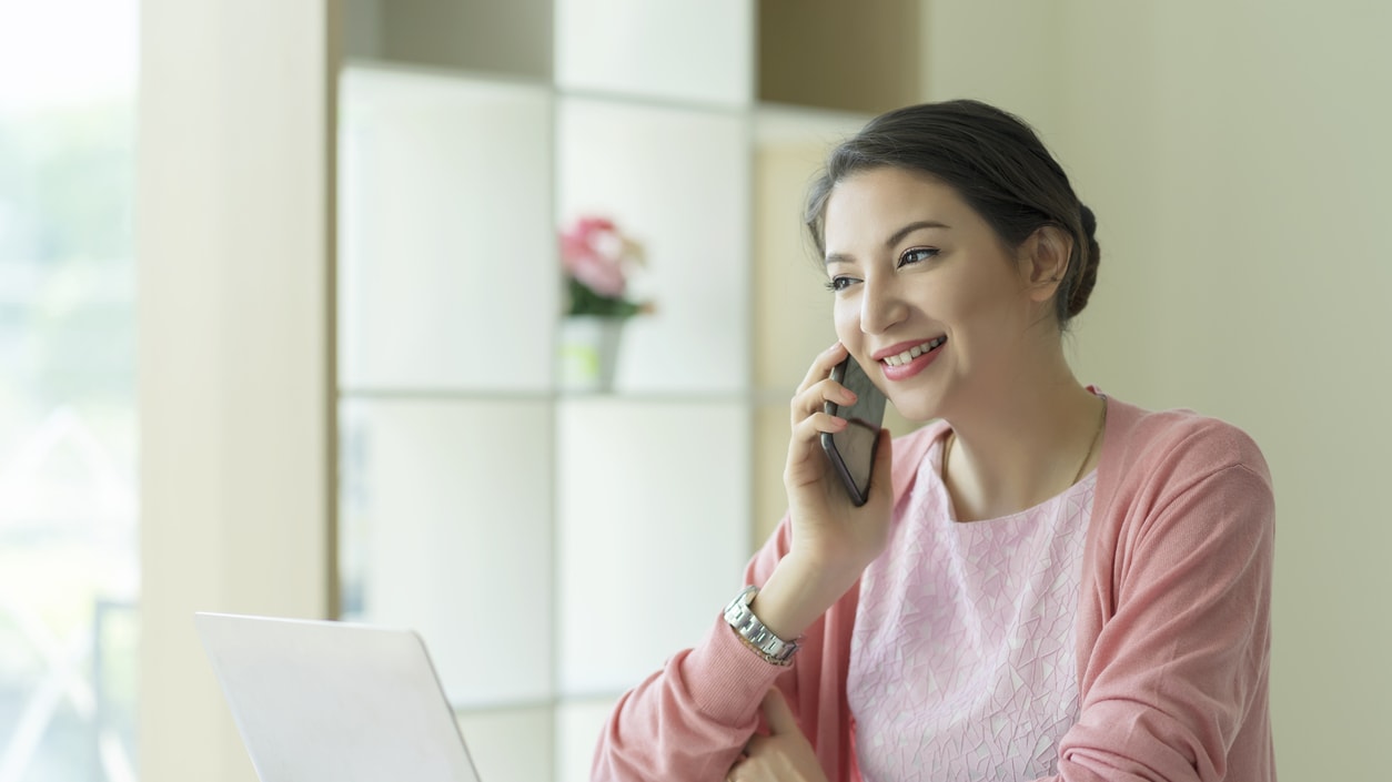 A woman is talking on the phone while sitting at her desk.