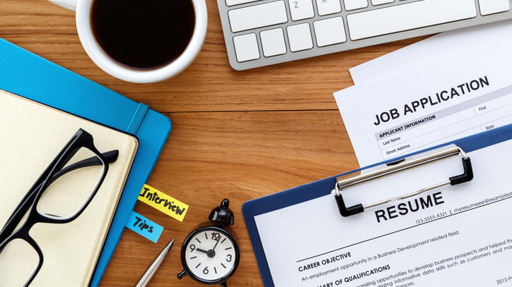 A job application on a desk with a pen and paper.