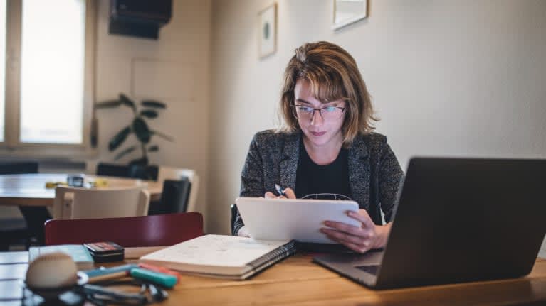 A woman working at a desk with a laptop.