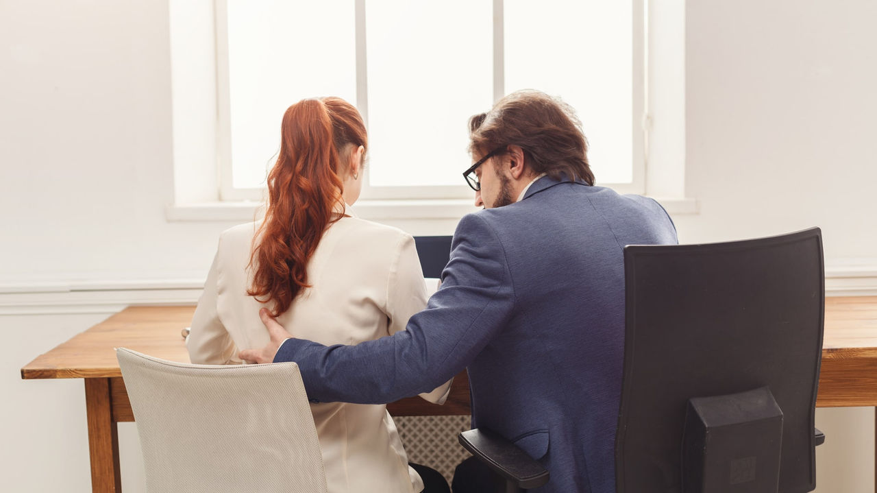 A man and woman sitting at a desk in an office.