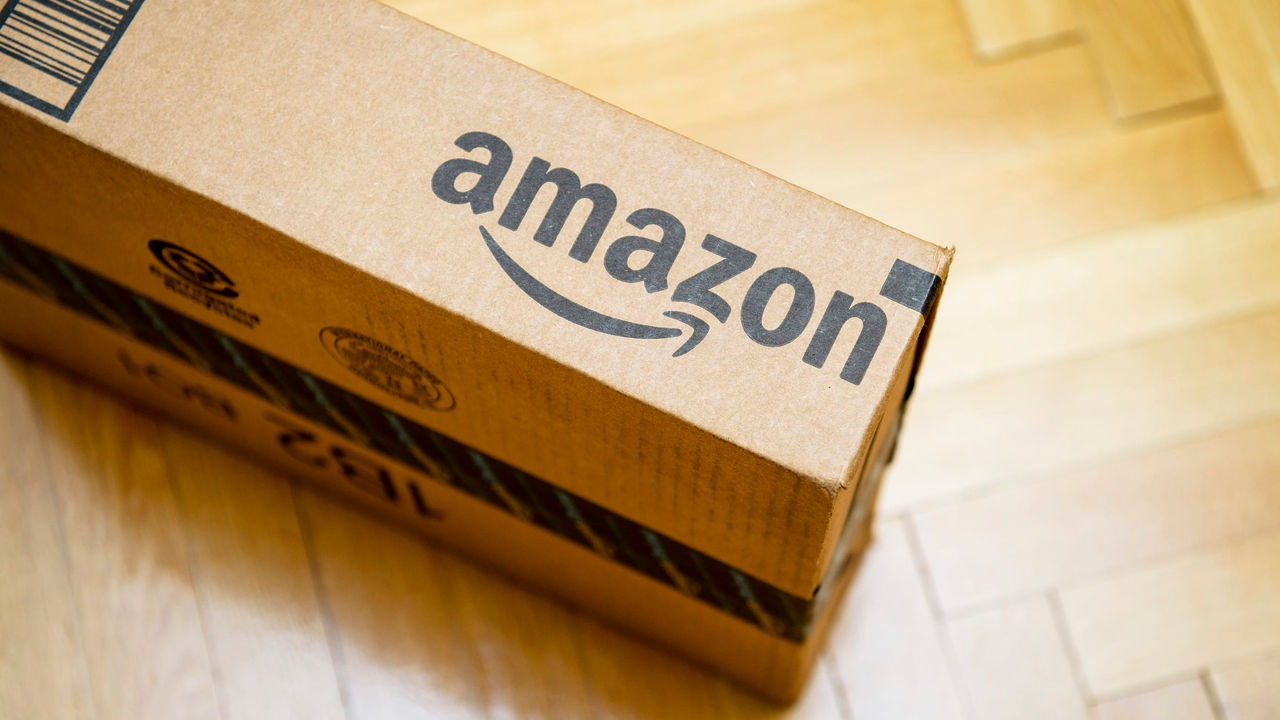 An amazon box sits on a wooden floor.