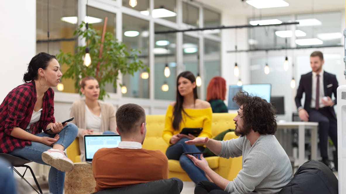 A group of people sitting on bean bags in an office.