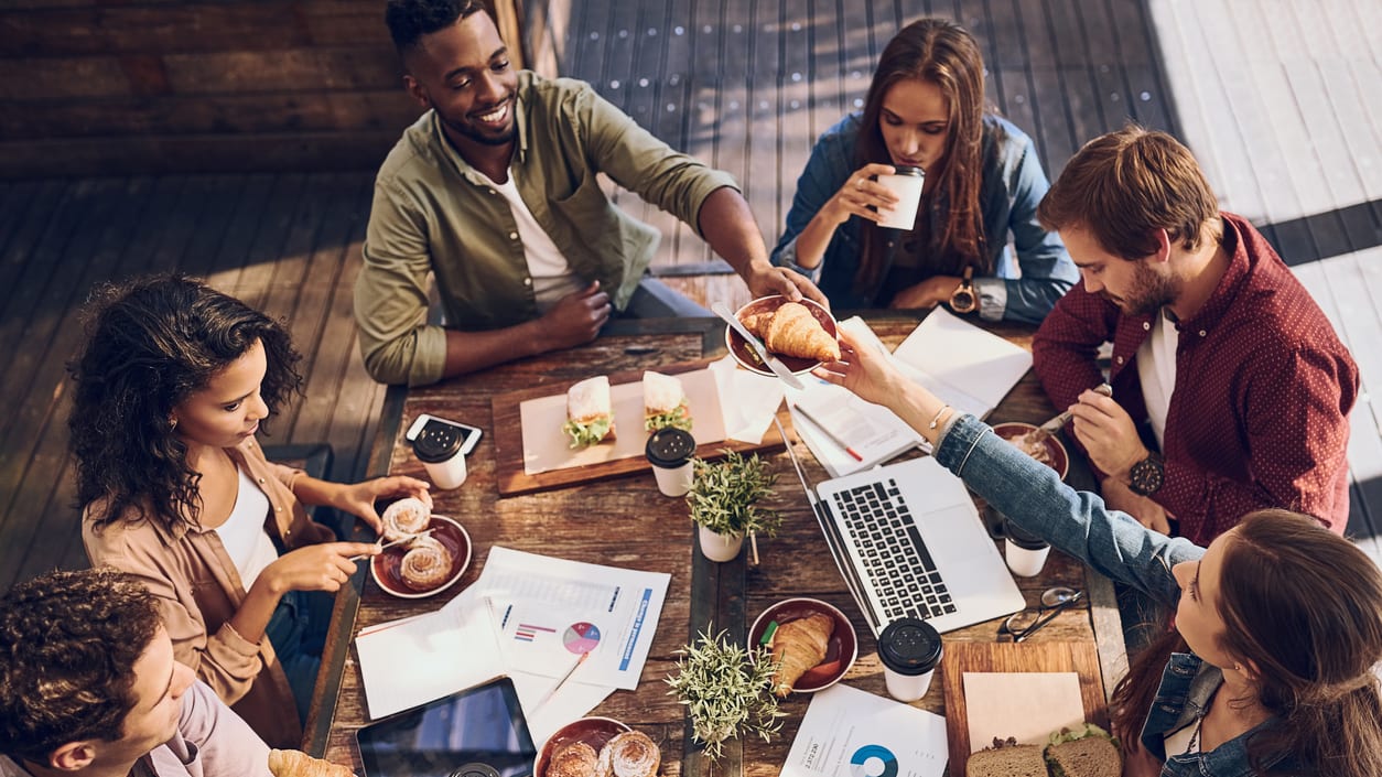 A group of people sitting around a table with laptops.