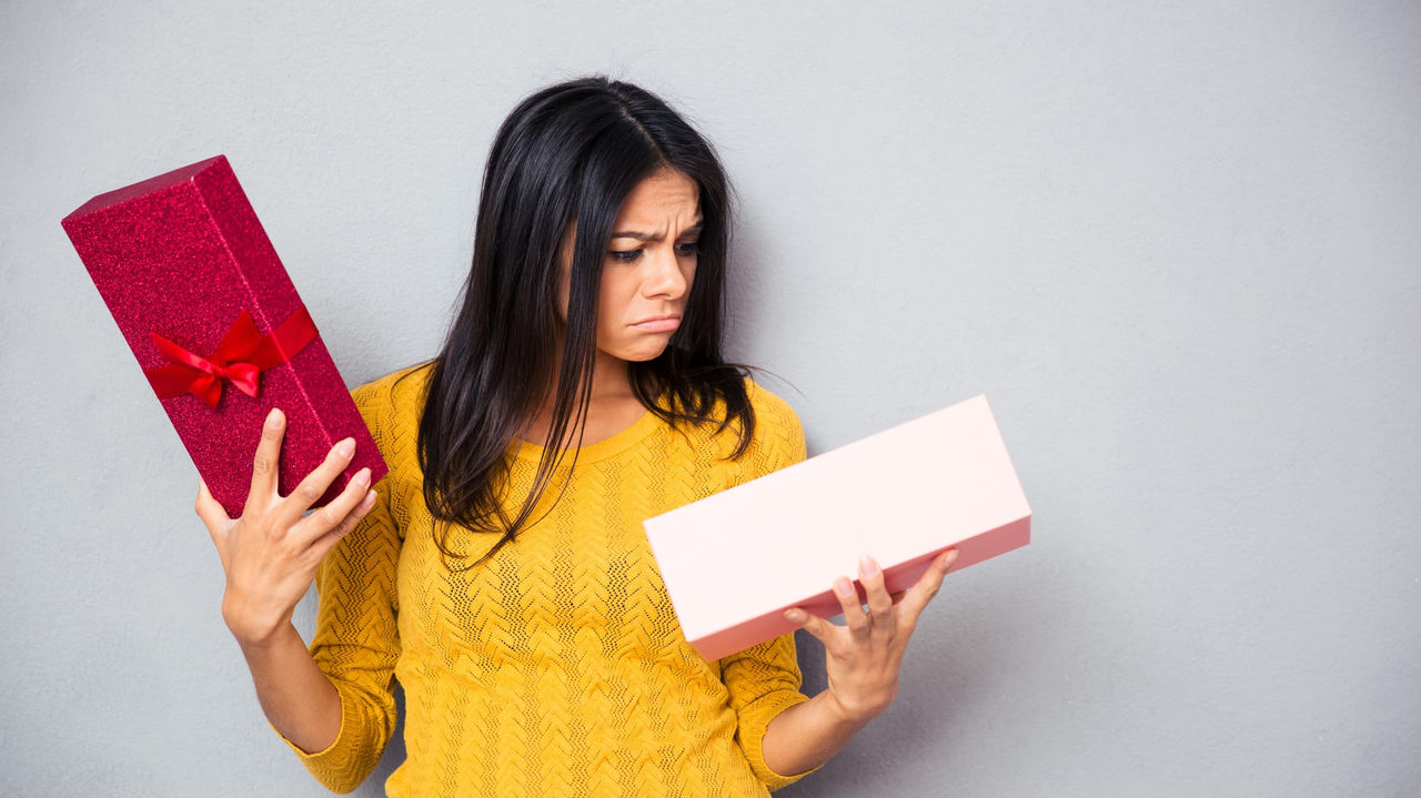 A woman holding a gift box and looking at it.