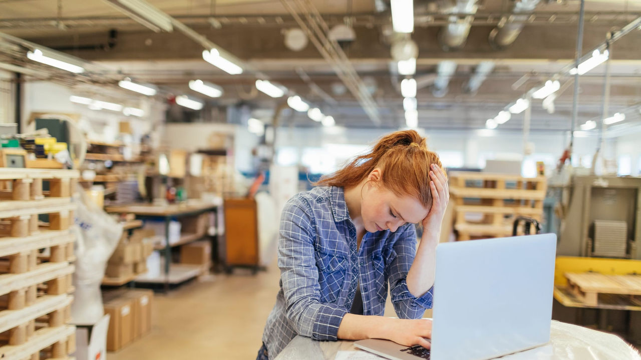 A woman working on a laptop in a warehouse.