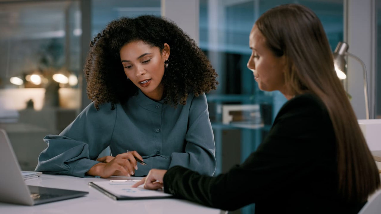 Two women talking at a table in an office.