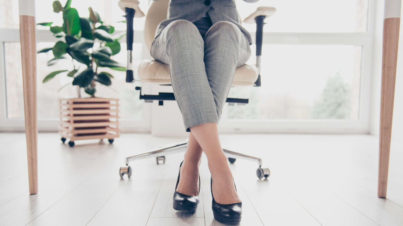 A woman in a business suit sitting on an office chair.