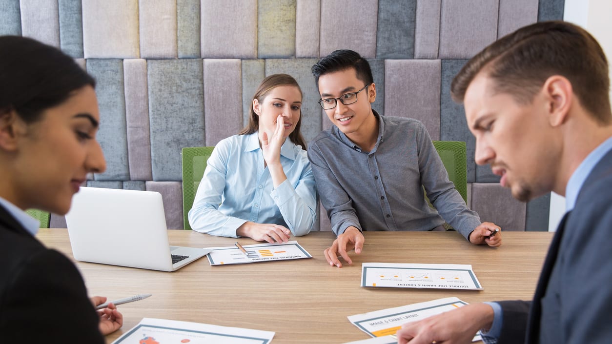 A group of business people sitting around a table in a meeting.