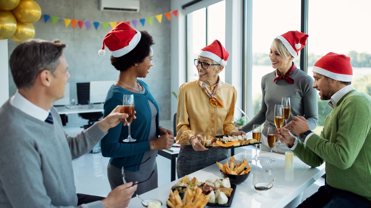 A group of people in santa hats at an office holiday party.