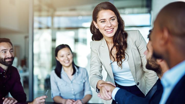 A group of business people shaking hands at a meeting.