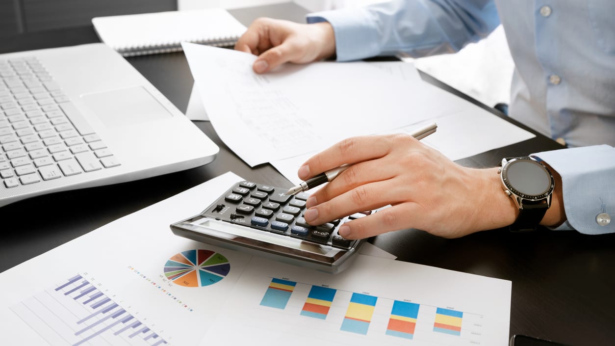 A man is using a calculator at his desk.